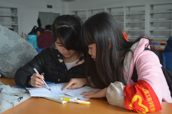 图为志愿者为特殊学生辅导功课