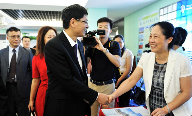 图为自治区党委常委、副主席蓝天立巡展并与副校长秦小云亲切握手